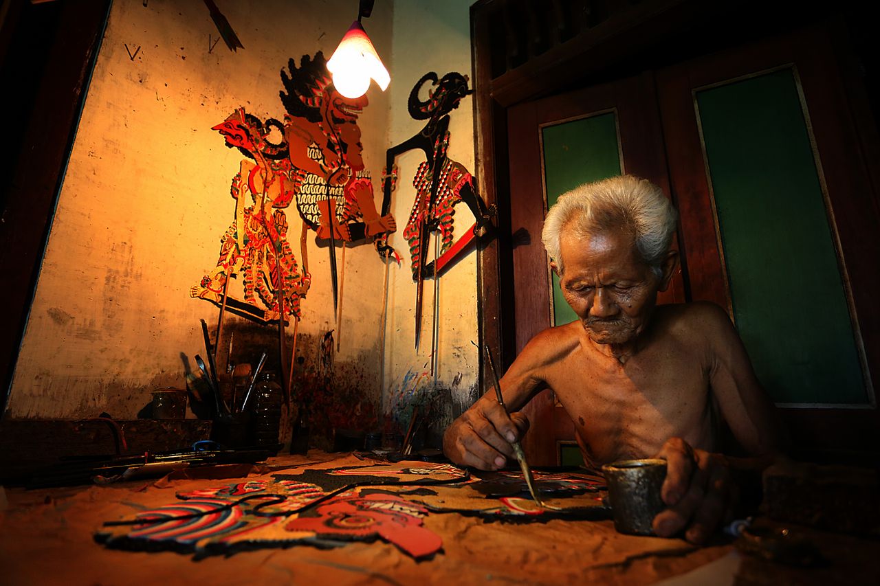 Crafting Captivating Headlines: Your awesome post title goes here Elderly craftsman creating intricate Wayang puppets in Surakarta, Indonesia.